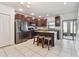 Well-lit kitchen with stainless steel appliances, dark cabinets, and a granite-topped island with seating at 5147 Brickwood Rise Dr, Wimauma, FL 33598