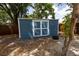 Blue wooden storage shed in backyard with double doors and white trim on a lot with mature trees at 5806 12Th S Ave, Tampa, FL 33619