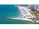 Beautiful aerial view of a white sand beach packed with vacationers, clear water, and a pier at 600 Bayway Blvd # 504, Clearwater Beach, FL 33767