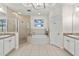 Spacious bathroom showcasing a soaking tub, glass enclosed shower, double vanity and tile flooring at 600 Bayway Blvd # 504, Clearwater Beach, FL 33767