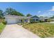Charming single-story home with a well-manicured lawn, white painted brick, attached garage, and concrete driveway at 8421 Millwood Dr, Tampa, FL 33615