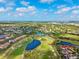 Aerial view of a community with a golf course, ponds and mature trees, set against a backdrop of blue skies at 8703 Bardmoor Blvd # 304, Seminole, FL 33777