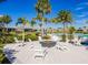 Outdoor fire pit surrounded by white Adirondack chairs, lush landscaping, and palm trees at 8732 Rain Song Rd, Sarasota, FL 34238