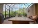 Screened lanai with comfortable seating and a fire table, offering a relaxing space with views of tropical foliage at 8732 Rain Song Rd, Sarasota, FL 34238