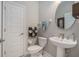 Half bathroom with a pedestal sink, a round mirror, and decorative accessories at 9843 Cabernet Ave, Seffner, FL 33584