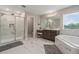 Elegant bathroom with a marble tile floor, soaking tub, glass shower, and double sink vanity with seating area at 9843 Cabernet Ave, Seffner, FL 33584