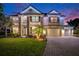 Striking two-story home with decorative lights, a manicured lawn, and a paved driveway leading to a three-car garage at 9843 Cabernet Ave, Seffner, FL 33584