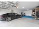 Organized three-car garage with epoxy flooring, home gym, ample storage, EV charger, and a car at 9843 Cabernet Ave, Seffner, FL 33584