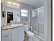 Bathroom with white vanity, framed mirror, walk-in shower with glass doors, and neutral tile flooring at 10717 Drummond Rd, Tampa, FL 33615