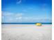Tranquil beach scene featuring a yellow sun shelter on the white sand under a blue sky with light clouds at 11 San Marco St # 407, Clearwater Beach, FL 33767