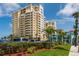 Elegant multi-story building with inviting balconies, surrounded by lush landscaping and palm trees at 11 San Marco St # 407, Clearwater Beach, FL 33767