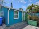 Charming turquoise home exterior featuring white trim, complemented by a vibrant green door and lush tropical landscaping at 126 119Th Ave, Treasure Island, FL 33706