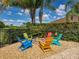 Charming backyard fire pit with colorful Adirondack chairs, perfect for entertaining in the landscaped outdoor space at 13302 Trailing Moss Dr, Dade City, FL 33525