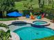 Backyard pool and spa area surrounded by lush landscaping and colorful chairs at 13302 Trailing Moss Dr, Dade City, FL 33525