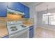 Kitchen featuring blue cabinets, a white range, and stylish backsplash, connecting to the dining area at 1424 Highland Ridge Cir, Brandon, FL 33510