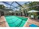 Enclosed backyard pool surrounded by brick patio and outdoor seating under a sunny, partly cloudy sky at 1868 Juarez S Way, St Petersburg, FL 33712