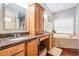 Bright bathroom featuring double sinks, granite countertops, soaking tub, and wood cabinetry at 19529 Lily Pond Ct, Brooksville, FL 34601