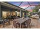 A spacious screened-in patio featuring an outdoor dining set, comfortable seating, and views of the surrounding yard at 19529 Lily Pond Ct, Brooksville, FL 34601