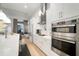 Modern kitchen features white cabinets, stainless steel appliances, and view of adjacent living space at 28853 Seedling St, Wesley Chapel, FL 33543