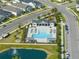Aerial view of a neighborhood pool with lounge chairs, playground and a water feature in an adjacent pond at 28853 Seedling St, Wesley Chapel, FL 33543