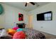 This bedroom features a ceiling fan, television, and bright accent pillows on a bed with gray patterned bedding at 2933 Maiden Grass Isle, Wesley Chapel, FL 33543