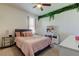 Charming bedroom featuring a vanity, hanging vines, and a comfortable bed with a pink comforter and accent pillows at 2933 Maiden Grass Isle, Wesley Chapel, FL 33543
