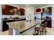 Kitchen island with granite countertops, stainless steel sink, seating and dark wood cabinets at 2933 Maiden Grass Isle, Wesley Chapel, FL 33543