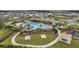 Aerial view showcasing a community pool with lounge chairs, cabanas, a playground, and green spaces at 2933 Maiden Grass Isle, Wesley Chapel, FL 33543