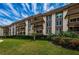 Exterior elevation of a multi-story condo building with balconies, landscaping, and a lush green lawn at 3021 Countryside Blvd # 45A, Clearwater, FL 33761