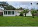 Spacious backyard featuring a sunroom, lush lawn, tropical palms, and complete privacy fence at 3919 Harrisburg Ne St, St Petersburg, FL 33703