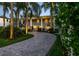 Elegant home with a circular driveway lined with palm trees, complemented by lush landscaping and exterior lighting at 4106 W Cleveland St, Tampa, FL 33609
