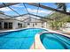 A screened-in backyard pool and spa combination featuring a lounging area and nearby doors to the house at 4106 W Cleveland St, Tampa, FL 33609