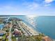 Aerial view showing a coastal community with houses, street parking, a beach, and glimmering ocean views at 4210 Headsail Dr, New Port Richey, FL 34652