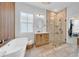 Bright bathroom features a soaking tub, walk-in shower with glass door, and a wooden vanity with neutral countertops at 422 Islebay Dr, Apollo Beach, FL 33572