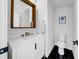 Well-lit powder room with modern fixtures, black and white tile, and a wood-framed mirror at 422 Islebay Dr, Apollo Beach, FL 33572