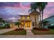 Two-story single Gathering home with a charming front porch, well-manicured lawn, and beautiful landscaping at sunset at 422 Islebay Dr, Apollo Beach, FL 33572