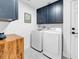 Functional laundry room with blue cabinets, modern machines, and patterned tile floor at 422 Islebay Dr, Apollo Beach, FL 33572