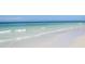 Expansive ocean view of tranquil waves meeting the white sandy beach shoreline on a bright, sunny day at 5430 Avenida Del Mare, Sarasota, FL 34242