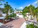 Charming home featuring a brick driveway, two-car garage, and beautifully landscaped yard with lush tropical plants at 5430 Avenida Del Mare, Sarasota, FL 34242