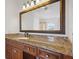 Bathroom vanity with warm cabinets, granite counters and detailed mirror at 8932 Rocky Creek Dr, Tampa, FL 33615
