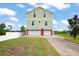 Two-story green home with a three-car garage and a large driveway with brick pavers at 8932 Rocky Creek Dr, Tampa, FL 33615
