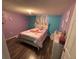 Colorful bedroom featuring purple walls, a unicorn-themed bedspread, and wood-look flooring at 9815 Wayside Ln, Port Richey, FL 34668