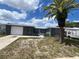 Charming single-story home features an attached garage, quaint front yard, and tropical landscaping with a mature palm tree at 9815 Wayside Ln, Port Richey, FL 34668