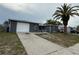 Cozy single-story home featuring a driveway, one-car garage, and a mature palm tree in the front yard at 9815 Wayside Ln, Port Richey, FL 34668