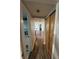 Hallway featuring wood-look flooring, storage closet, and view of the living and bathroom areas at 9815 Wayside Ln, Port Richey, FL 34668