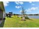 Large backyard with a play structure and pond view, perfect for outdoor activities and relaxation by the water at 11773 Little River Way, Parrish, FL 34219
