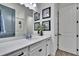 Well-lit bathroom featuring a large mirror, framed artwork, and white cabinetry at 11773 Little River Way, Parrish, FL 34219