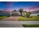 Beautiful exterior view of home at dusk, with a brick driveway, manicured lawn, and lovely landscape lighting at 11773 Little River Way, Parrish, FL 34219