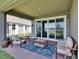 Relaxing covered patio with cozy seating, a stylish rug, and a view of the backyard leading to the serene lake at 11773 Little River Way, Parrish, FL 34219