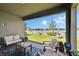 Comfortable covered patio featuring cozy seating, a decorative rug, and a beautiful view of the backyard and lake at 11773 Little River Way, Parrish, FL 34219